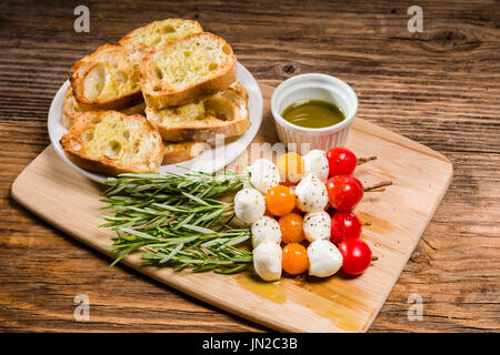 Fromage et pain tomate bouchées sur des brochettes de romarin Banque D'Images