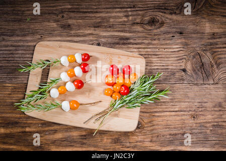 Boules de fromage et les tomates sur des brochettes de romarin Banque D'Images