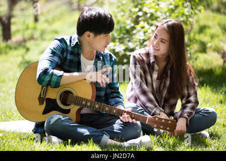 Jeune couple jouant de la guitare sur l'herbe Banque D'Images