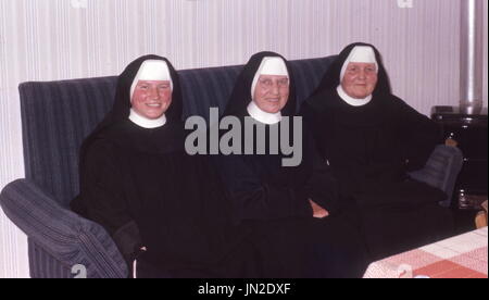 C1973. Trois religieuses en habitude assis sur un canapé souriant pour appareil photo. Photographie par Tony Henshaw Banque D'Images