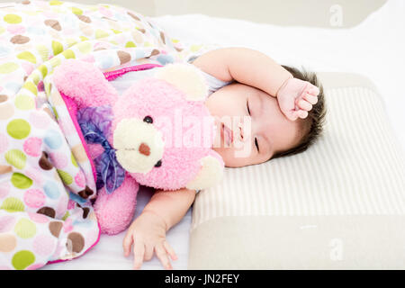 Portrait de bébé endormi sur un lit de poupée ours Banque D'Images