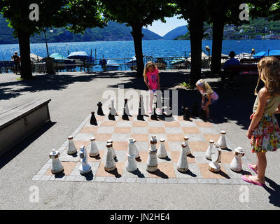 Enfants Enfants famille filles jouant avec un échiquier géant au bord du lac de Lugano en Italie Banque D'Images