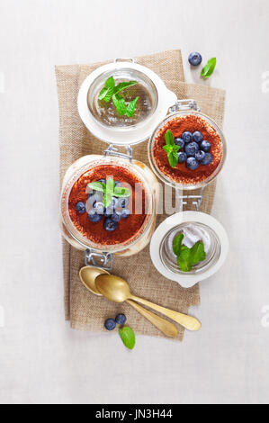 Gâteau tiramisu maison dessert italien traditionnel dans des bocaux en verre sur la table en pierre blanche Banque D'Images