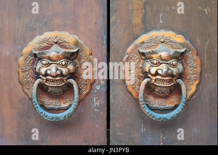 Heurtoirs de porte de couleur d'or chinois sur une barrière en bois Banque D'Images