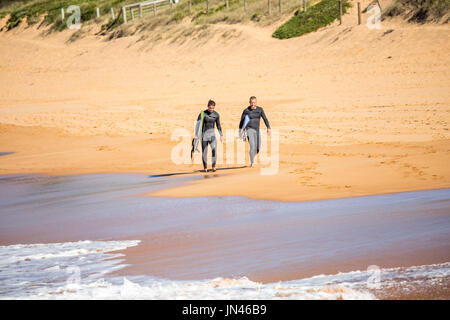 Deux combinaisons de surf en marchant le long de la plage d'Avalon à Sydney Banque D'Images