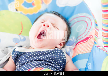 Portrait d'un adorable petit infant baby girl le bâillement avant de dormir sur le lit à l'intérieur Banque D'Images