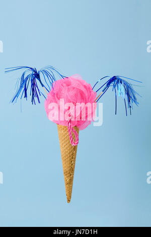 Un cornet de crème glacée dont l'écope est remplacé par un plastique rose Loofah éponge. Composition photographique drôle et décalé. Fun, minime et couleur surréaliste Banque D'Images