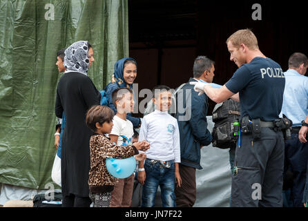 Passau, Allemagne - le 2 août 2015 : un policier allemand prend soin d'un jeune enfant de réfugiés en provenance de Syrie à la zone d'enregistrement à Passau, Bavière. T Banque D'Images