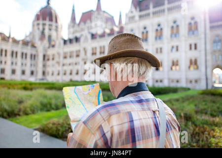 Tourisme Senior man in hat recherche de destination sur la carte au parlement hongrois, Budapest, Hongrie Banque D'Images