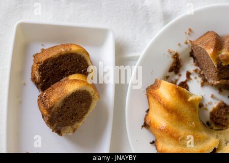 Vue de dessus sur deux tranches de gluten free marmor traditionnel gâteau de Madère sur tableau blanc vêtu Banque D'Images