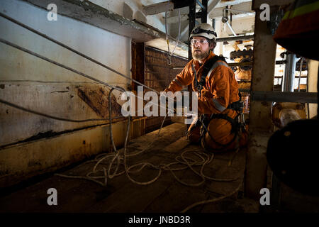 Corde industriel technicien d'accès mise en place d'un système de transport recsue, portant une combinaison orange. crédit : lee ramsden / alamy Banque D'Images