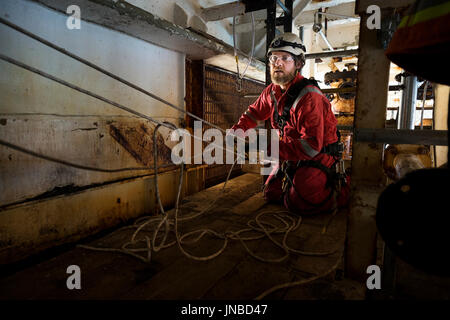 Une corde industriel technicien d'accès mise en place d'un système de transport recsue, vêtu d'une combinaison rouge. crédit : lee ramsden / alamy Banque D'Images