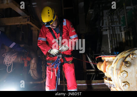 Une corde industriel technicien d'accès configuration de son harnais, le port d'une combinaison rouge. crédit : lee ramsden / alamy Banque D'Images