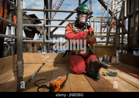 Un travailleur industriel, le port d'appareil respiratoire complet comme sur le point de percer dans un tuyau et effectuer un test de gaz. crédit : lee ramsden / alamy Banque D'Images