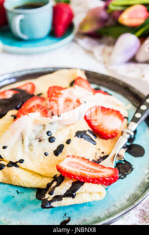 L'heure du petit-déjeuner avec fraises fraîches, chocolat et crêpes sur fond rustique Banque D'Images