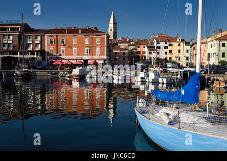 Marina de la vieille ville de pêcheurs d'Izola Slovénie sur la côte Adriatique avec l'église paroissiale de St Maur tower et bâtiments reflètent colorés Banque D'Images