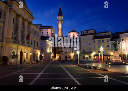 La place Tartini Piran en Slovénie avec l'Hôtel de Ville, maison vénitienne, statue, Tartini et St George's Parish Church avec baptistère au crépuscule, crépuscule Banque D'Images