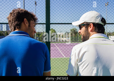 Deux joueurs professionnels se reposant après une partie de tennis. Ils sont amis et sont assis en appui pour le jeu. Ils sont heureux et rire. Banque D'Images