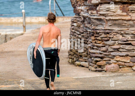 Jeune adolescent mâle australien portant sa planche de surf à la plage d'Avalon,Sydney, Australie Banque D'Images