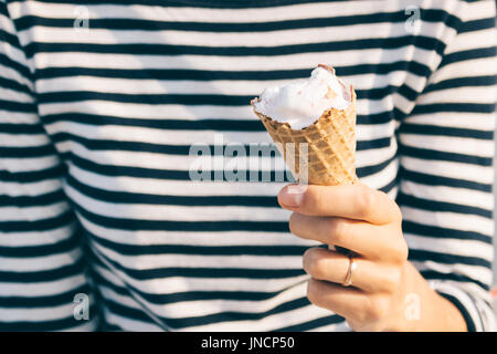 Portrait d'une femme dans un T-shirt à rayures tenant une glace dans sa main à l'extérieur Banque D'Images