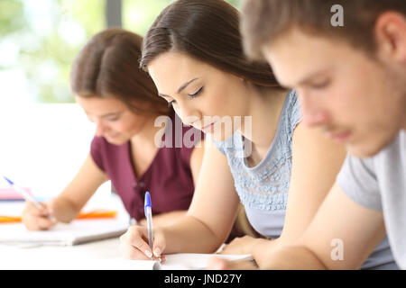 Près de trois étudiants sérieux en prenant des notes dans une salle de classe Banque D'Images