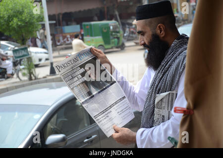 L'homme lit un journal pakistanais avec front page news de Pakistanais renversé l'ancien Premier Ministre Nawaz Sharif.Cour suprême du Pakistan le 28 Juillet Le Premier Ministre Nawaz Sharif exclu de la vie publique sur les allégations de corruption, d'exécution d'une décision qui exclut de la Premiership pour la troisième fois. La décision plonge le pays dans les troubles politiques environ un an avant les élections générales programmées qui aurait vu Sharif devenir le premier premier ministre pakistanais, d'achever un cycle complet de cinq ans. (Photo par Rana Sajid Hussain/Pacific Press) Banque D'Images