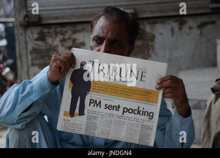 L'homme lit un journal pakistanais avec front page news de Pakistanais renversé l'ancien Premier Ministre Nawaz Sharif.Cour suprême du Pakistan le 28 Juillet Le Premier Ministre Nawaz Sharif exclu de la vie publique sur les allégations de corruption, d'exécution d'une décision qui exclut de la Premiership pour la troisième fois. La décision plonge le pays dans les troubles politiques environ un an avant les élections générales programmées qui aurait vu Sharif devenir le premier premier ministre pakistanais, d'achever un cycle complet de cinq ans. (Photo par Rana Sajid Hussain/Pacific Press) Banque D'Images