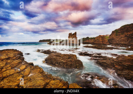 Côte rocheuses autour de la plage de bombo dans Kiama ville sur la côte du Pacifique de l'Australie. Flux surf floue à terre des falaises de grès érodé et cathédrale boul Banque D'Images