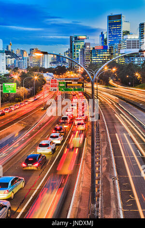 Autoroute à voies multiples en passant par les banlieues densément peuplés du nord de Sydney en Australie au coucher du soleil. Voitures floue coincé dans des embouteillages aux heures de pointe Banque D'Images