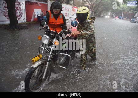 Jinjiang, Chine. 30 juillet, 2017. Un policier, un citoyen permet de pousser une extinction moteur de moto dans Jinjiang, sud-est de la Chine, la province du Fujian, le 30 juillet 2017. Le typhon Nesat, le neuvième typhon de l'année, a touché terre à Fujian dimanche matin. Sans répit, le typhon Haitang, la dixième typhon de l'année, était prévu à la terre dans le sud de Taïwan dimanche soir et faire un second atterrissage en quelque part entre Xiapu et Jinjiang dans la province du Fujian lundi matin, selon le Centre météorologique national. Source : Xinhua/Alamy Live News Banque D'Images