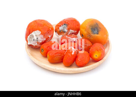 Tomate pourrie sur plaque de bois isolé sur fond blanc Banque D'Images