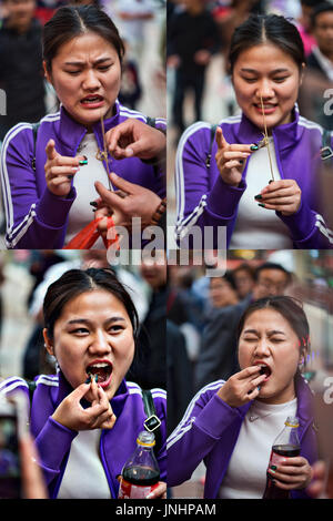 Jeune chinoise dans le sport sur le marché de Wangfujing, Beijing, Chine d'essayer pour la première fois le scorpion sur le stick, rue de spécialité de la nourriture. Banque D'Images