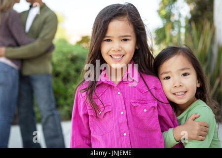 Heureux les petites filles avec leurs parents dans l'arrière-plan. Banque D'Images