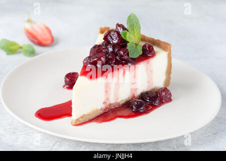 Tranche de gâteau au fromage avec la sauce aux cerises sur plaque blanche, vue rapprochée Banque D'Images