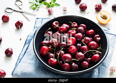 Les cerises dans un bol noir vue rapprochée. La récolte des petits fruits biologiques frais locaux Banque D'Images