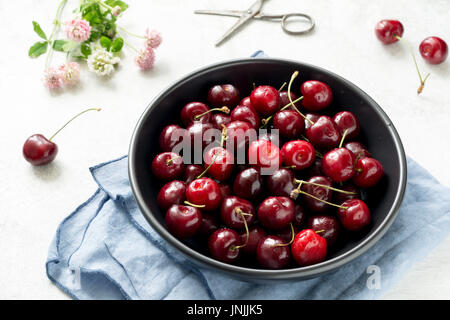 Les cerises dans un bol noir vue rapprochée. La récolte des petits fruits biologiques frais locaux Banque D'Images