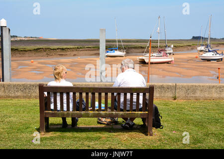Couple de personnes âgées assis sur banc en bois à au bateaux dans Wells-next-the-sea à Norfolk en Angleterre Banque D'Images