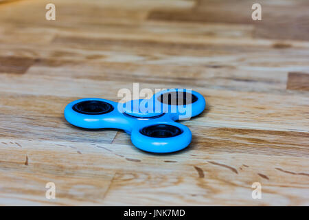 Un moderne bleu (turquoise) fidget spinner allongé sur le bois Banque D'Images