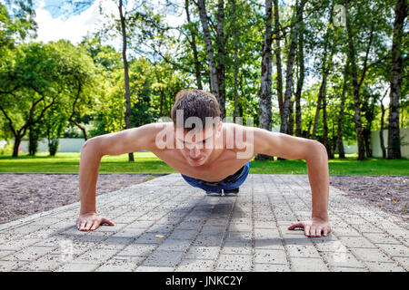 Jeune homme pratiquant de push-up dans la journée d'été sur le parc libre Banque D'Images
