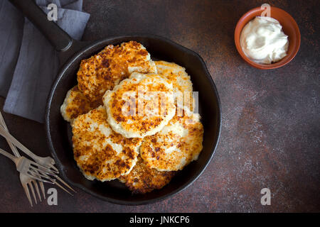 Maison rustique dans des crêpes pâte poêle en fonte avec sauce au yogourt pour le petit-déjeuner, style de campagne. L'alimentation saine, de fromage cottage rustique des crêpes. Banque D'Images