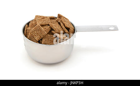 Shredded Wheat maltée biscuits céréales petit déjeuner dans une tasse mesurer, isolé sur fond blanc Banque D'Images