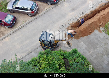 VILNIUS, LITUANIE - Juillet 27, 2017 : vue aérienne sur les travailleurs qui creusent une tranchée dans la terre de sable et de jeter un nouveau câble électrique Banque D'Images