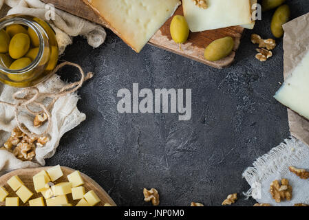 Assiette de fromages de différents types de fromage à pâte dure (suédois, espagnol, italien manchego fromage pecorino toscano) aux olives vertes dans un bocal en verre et les noix Banque D'Images