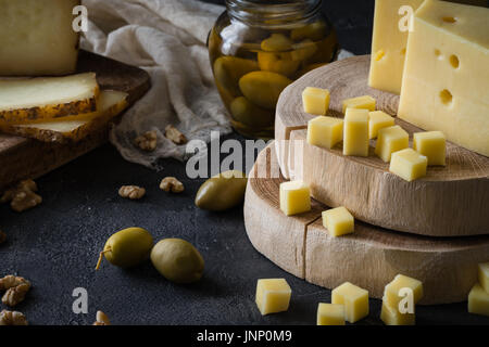 Assiette de fromage de fromage à pâte dure et tranchées suédois et italien Pecorino Toscano) sur des planches de bois, aux olives vertes dans un bocal en verre et les noix Banque D'Images