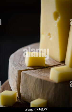 Close up of Swedish version fromage jaune avec des trous sur les tranches de bois haché sur fond rustique foncé Banque D'Images