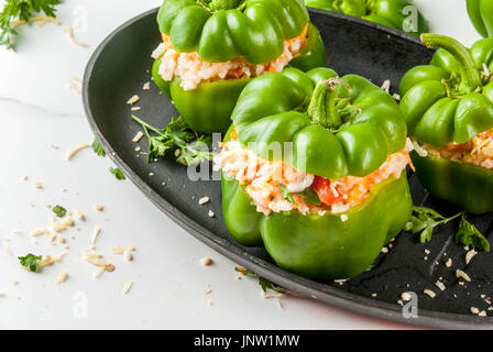 Recettes d'automne. Accueil poivron farci avec de la viande hachée, les carottes, tomates, herbes, fromage. Processus de cuisson. Table en marbre blanc. Poivron farci prêt Banque D'Images