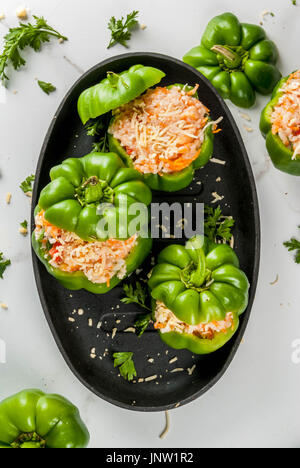 Recettes d'automne. Accueil poivron farci avec de la viande hachée, les carottes, tomates, herbes, fromage. Processus de cuisson. Table en marbre blanc. Poivron farci prêt Banque D'Images