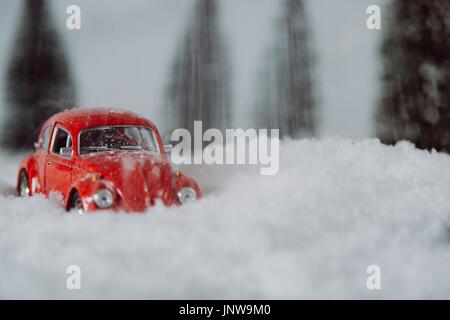 Petite voiture rouge toy coincé dans la neige en forêt miniature Banque D'Images