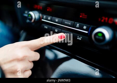 Femme allume la climatisation dans la voiture. Intérieur voiture moderne Banque D'Images