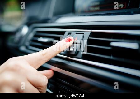 Femme active les feux de secours dans la voiture. Intérieur voiture moderne Banque D'Images